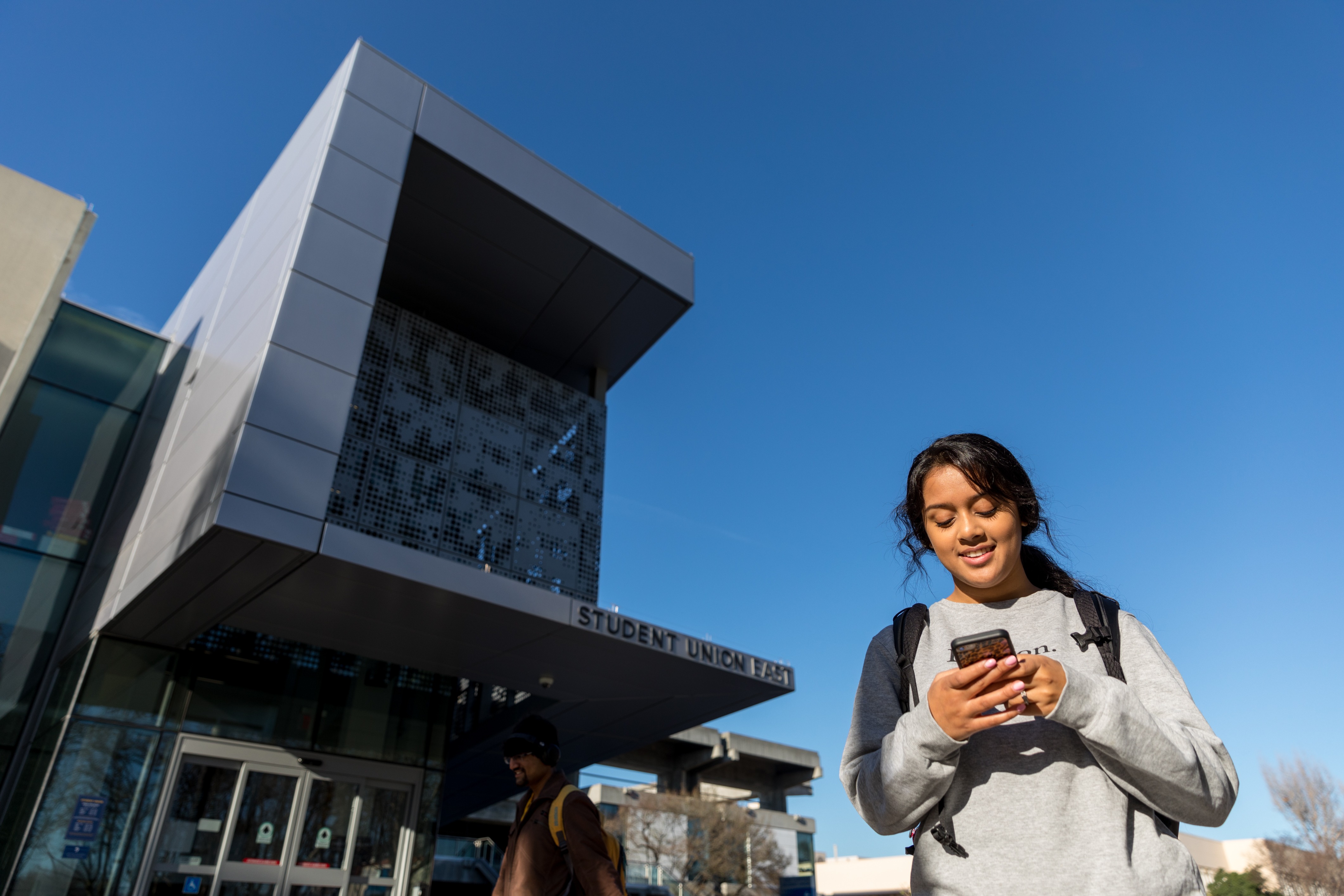 Girl looks down at her phone watching a video tour of SJSU